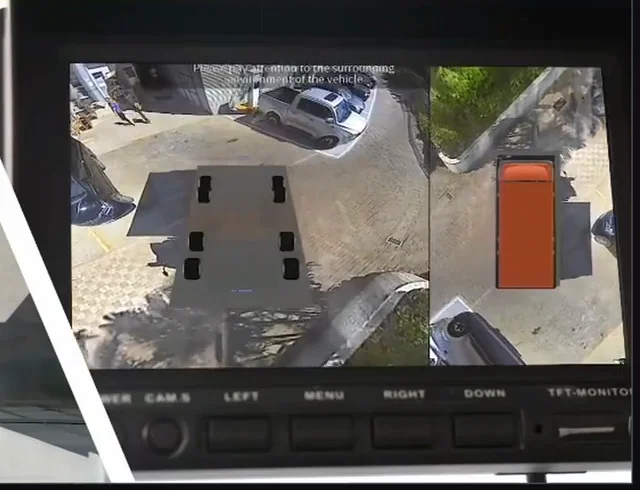 A cab screen showing the AI 360 bird’s-eye surround view of a vehicle beside a rear camera view