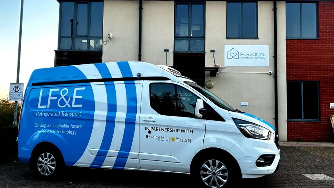 An LF and E Refrigerated Transport van in blue and white livery parked outside a pharmacy unit