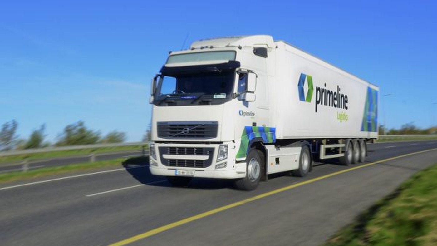 A white Primeline Logistics articulated refrigerated lorry travelling on a dual carriageway