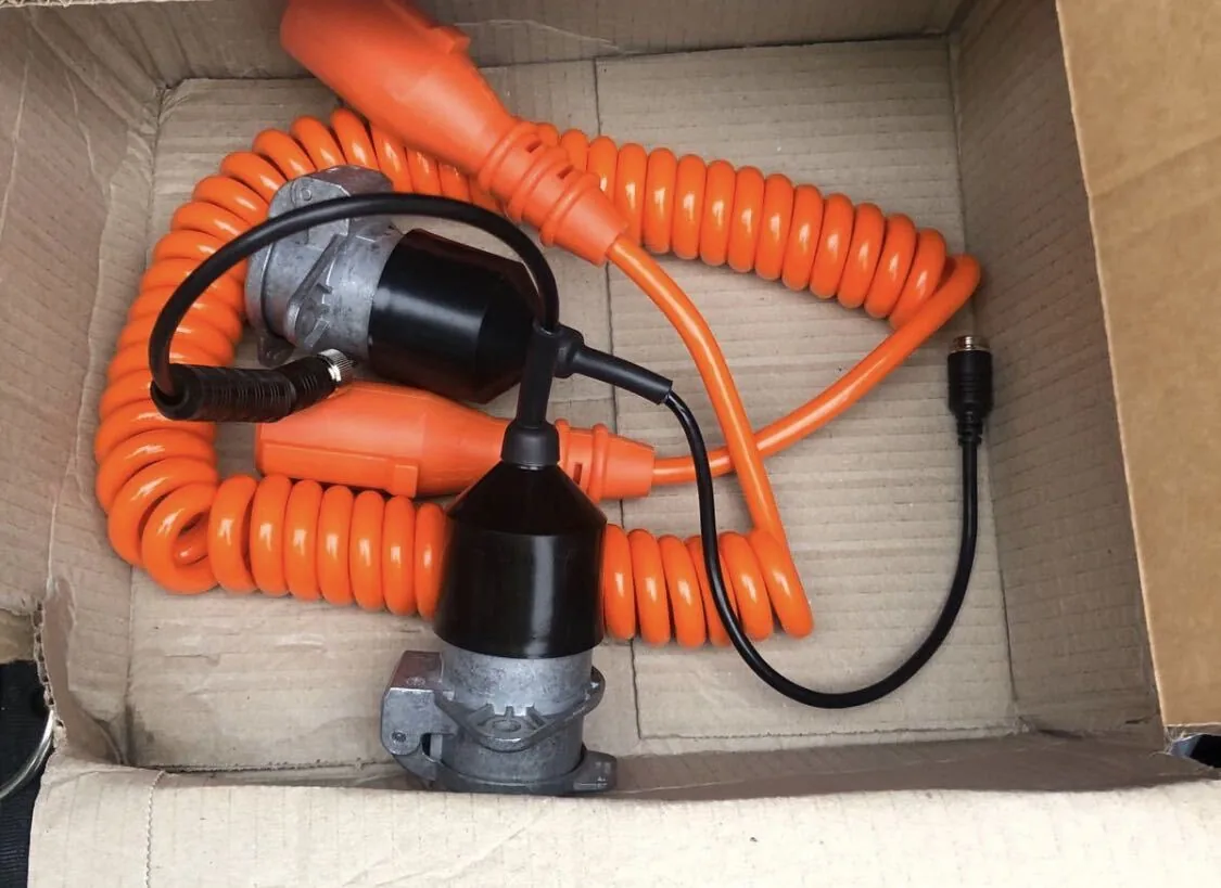 An orange coiled camera suzi in a box with its tractor and trailer sockets and camera leads