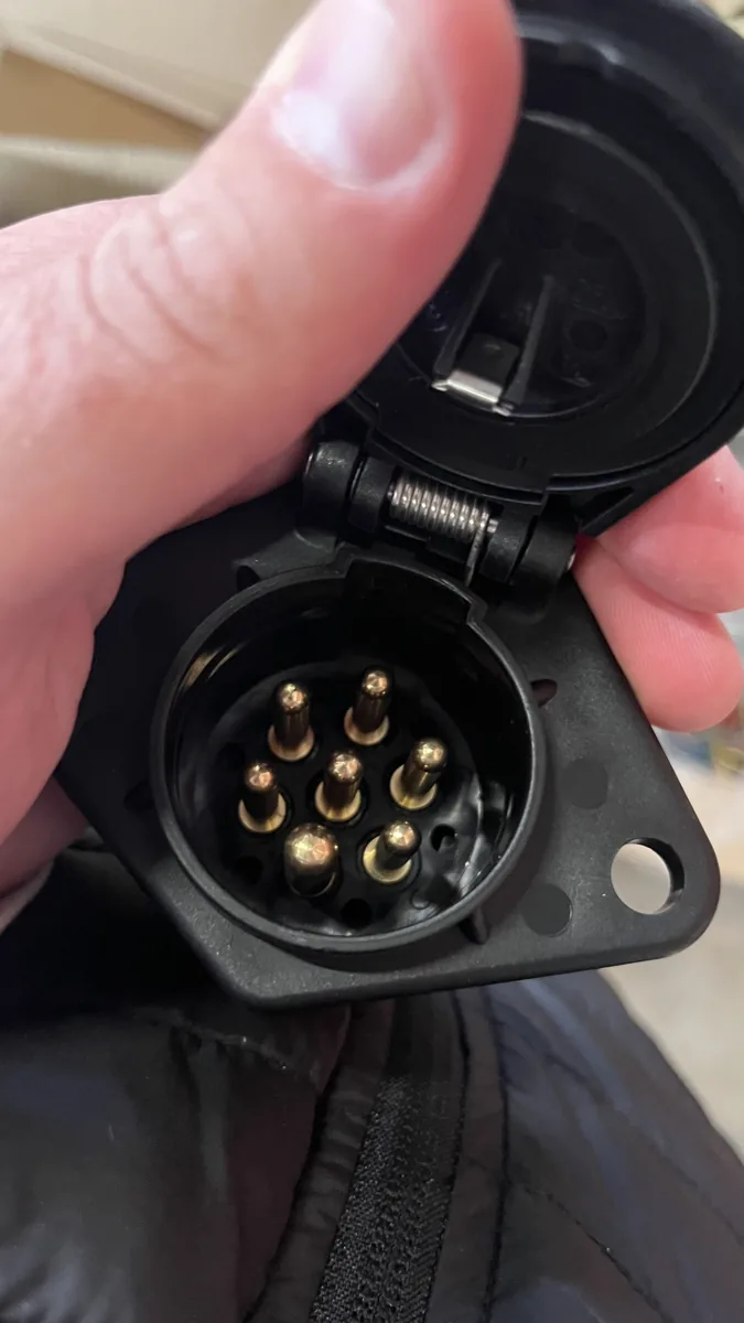 A 7-pin camera socket with its lid open, the large pin at the bottom
